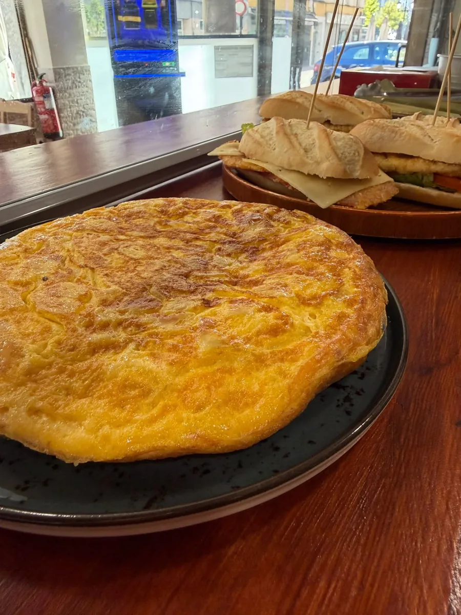 Tortilla entera y bocadillos sobre la barra de Manas